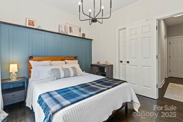 bedroom featuring dark wood-style flooring and a chandelier