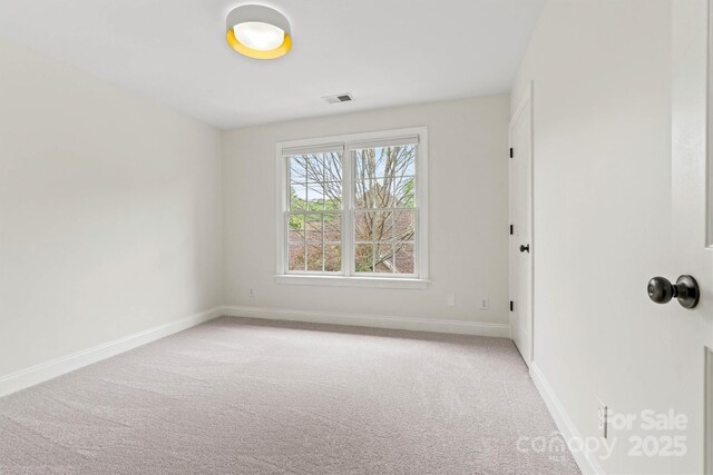 empty room featuring light colored carpet, baseboards, and visible vents