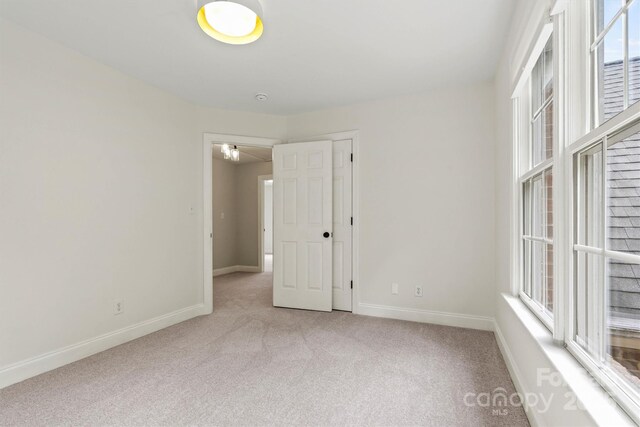 carpeted spare room featuring a healthy amount of sunlight and baseboards