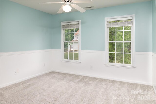 carpeted spare room with visible vents and a ceiling fan