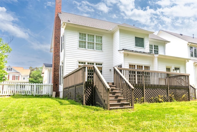 back of property featuring a deck, fence, and a lawn