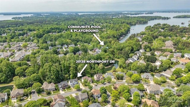 drone / aerial view featuring a wooded view, a water view, and a residential view