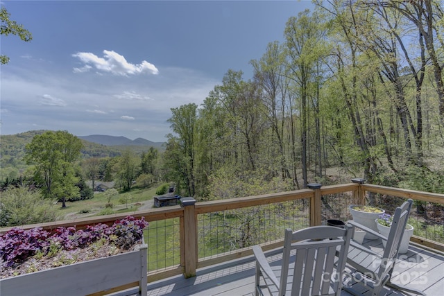 wooden deck featuring a forest view and a mountain view