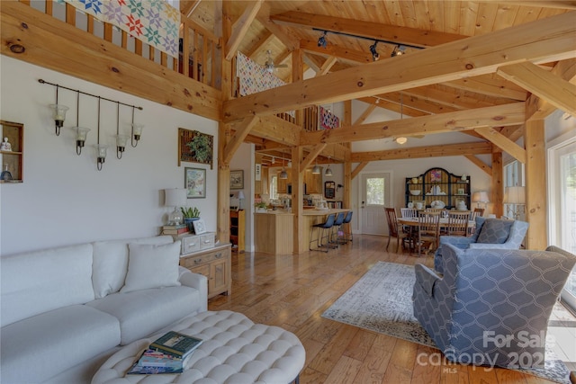 living area featuring lofted ceiling with beams, wooden ceiling, and light wood-type flooring