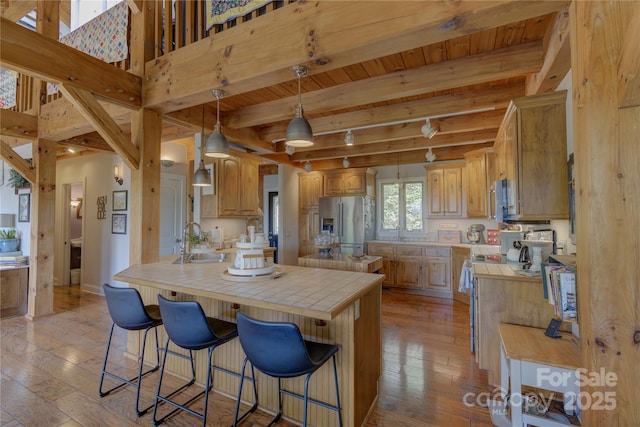 kitchen with stainless steel appliances, a sink, tile countertops, and a breakfast bar area
