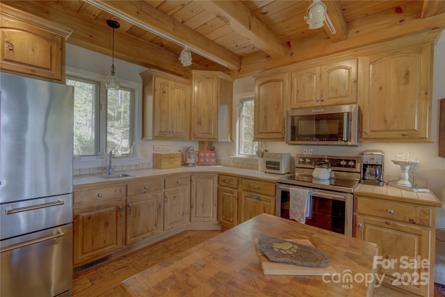 kitchen with plenty of natural light, light wood-style floors, wood ceiling, tile countertops, and appliances with stainless steel finishes