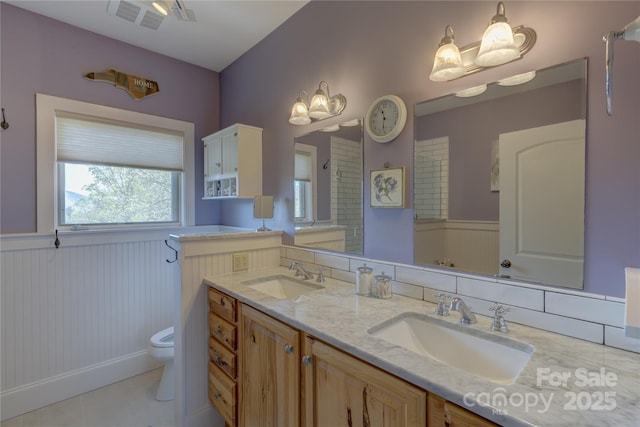bathroom with wainscoting, visible vents, a sink, and toilet