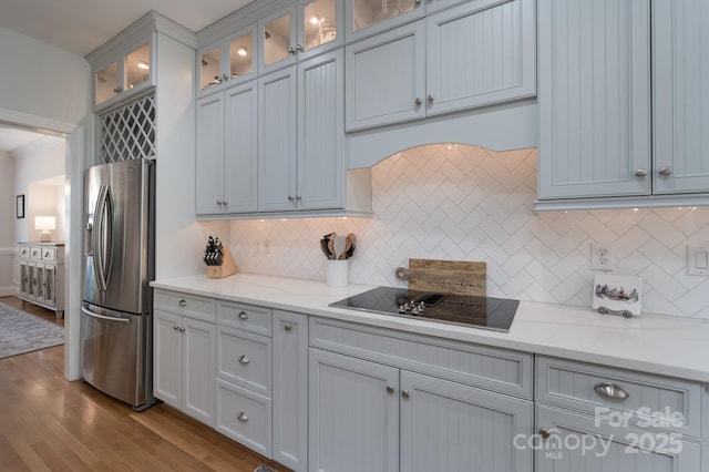 kitchen featuring stainless steel fridge, tasteful backsplash, dark wood-style flooring, and black electric stovetop