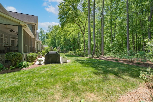 view of yard with a sunroom and a ceiling fan
