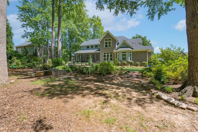 rear view of property with brick siding and a sunroom