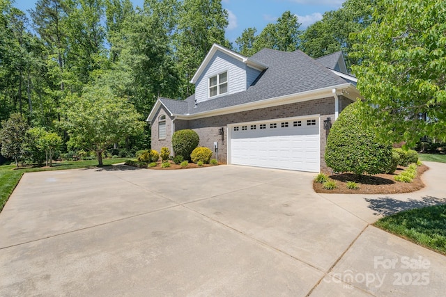 view of home's exterior with an attached garage, a shingled roof, concrete driveway, and brick siding