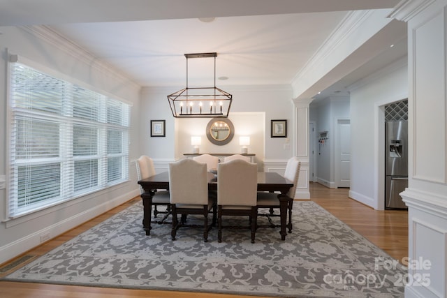 dining space featuring a notable chandelier, visible vents, ornamental molding, and light wood-type flooring
