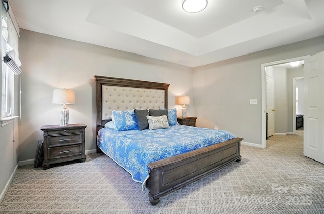 carpeted bedroom with baseboards and a tray ceiling