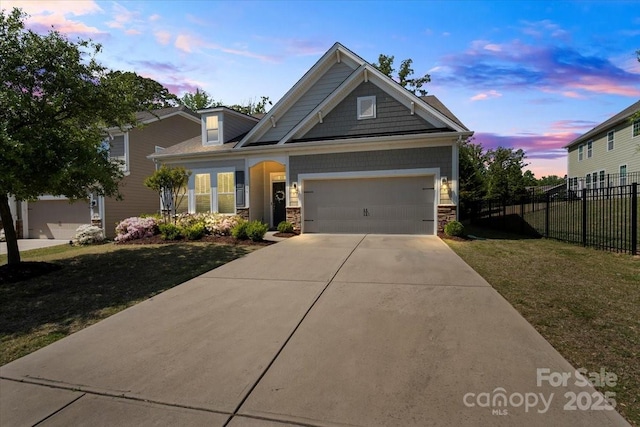 craftsman house with driveway, stone siding, fence, a yard, and a garage