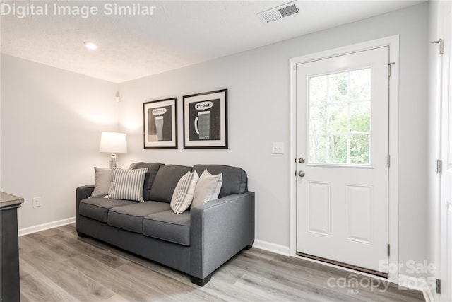 living area featuring light wood finished floors, visible vents, and baseboards