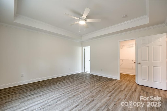 spare room featuring ceiling fan, wood finished floors, a raised ceiling, and crown molding