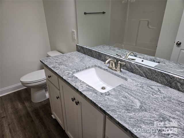 bathroom featuring toilet, wood finished floors, vanity, a shower, and baseboards