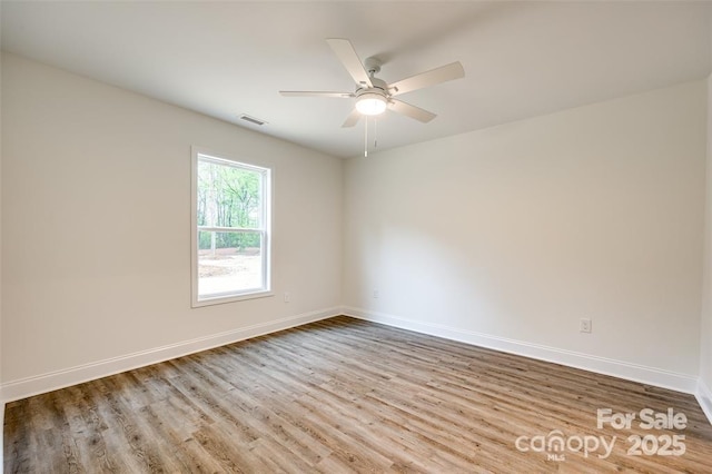 spare room featuring baseboards, a ceiling fan, wood finished floors, and visible vents