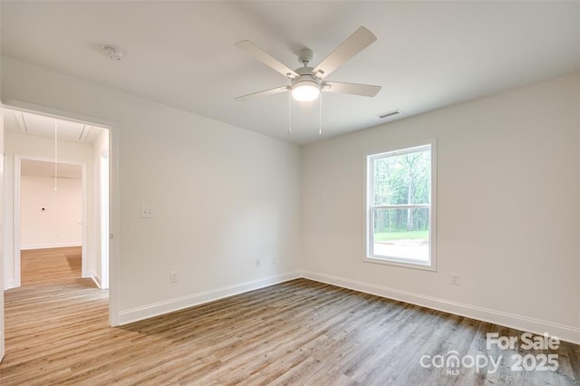 empty room with attic access, baseboards, wood finished floors, and visible vents