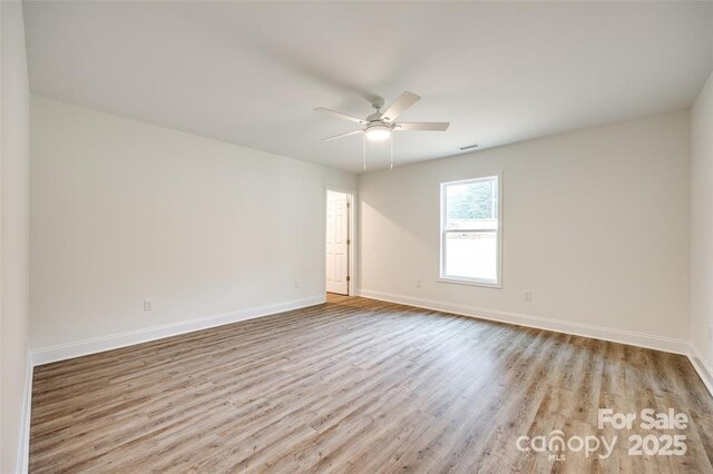 empty room featuring baseboards, a ceiling fan, and wood finished floors