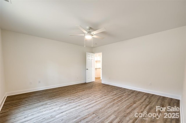 spare room with visible vents, baseboards, wood finished floors, and ceiling fan
