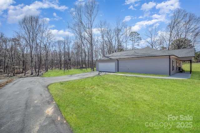 view of side of property featuring roof with shingles, driveway, a yard, and a garage