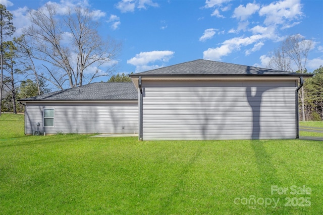 exterior space featuring a shingled roof and a yard