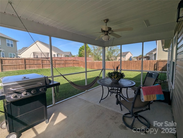 sunroom featuring ceiling fan and a residential view