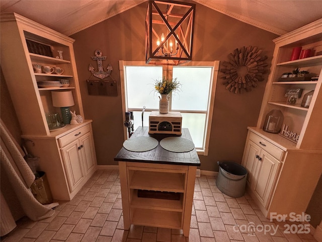 127 Hummingbird Cir, New London, NC 28127 - dining area featuring crown molding, vaulted ceiling, brick floor, and an inviting chandelier