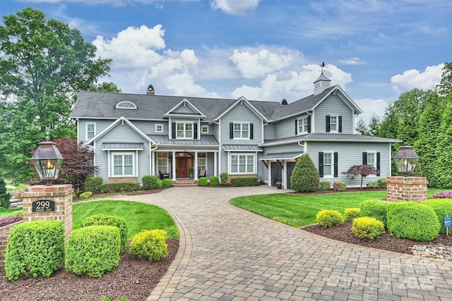 view of front facade featuring a front lawn, decorative driveway, a standing seam roof, a shingled roof, and an attached garage