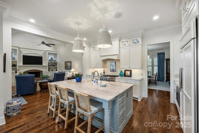 kitchen featuring light stone counters, open floor plan, white cabinets, and ornamental molding