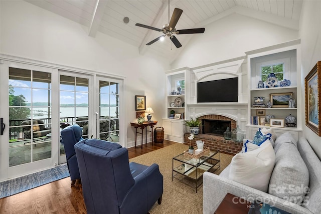 living area with ceiling fan, a fireplace, high vaulted ceiling, wood finished floors, and beamed ceiling