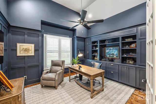 office space featuring ceiling fan, a decorative wall, and light wood-style flooring