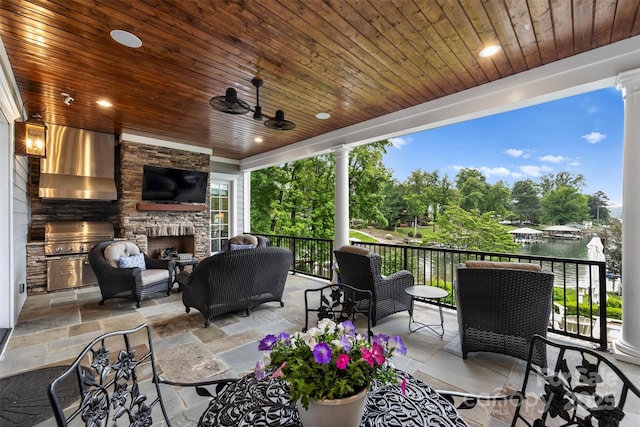 view of patio / terrace with area for grilling, a ceiling fan, and an outdoor living space with a fireplace