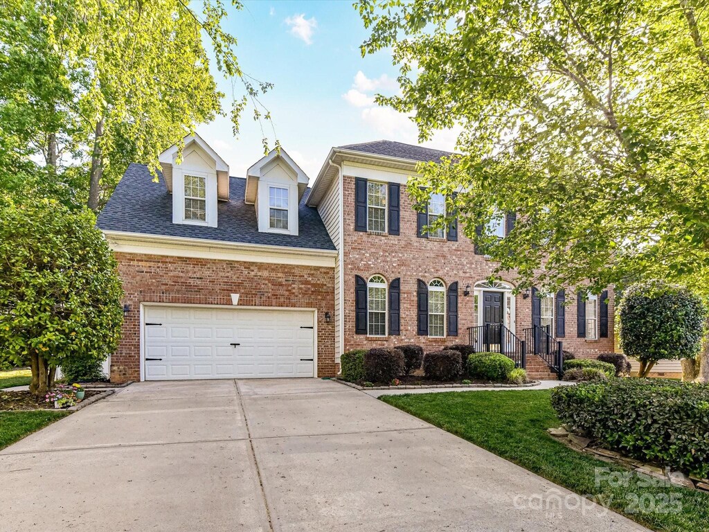 6005 Abergele Ln, Matthews, NC 28104 - colonial house featuring brick siding, a shingled roof, a garage, and driveway