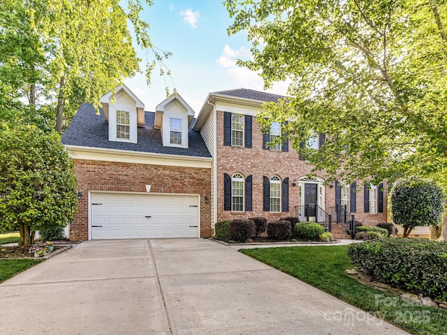 6005 Abergele Ln, Matthews, NC 28104 - colonial house featuring brick siding, a shingled roof, a garage, and driveway