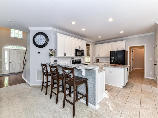 6005 Abergele Ln, Matthews, NC 28104 - kitchen featuring crown molding, a peninsula, a kitchen island, tasteful backsplash, and black appliances