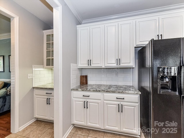 6005 Abergele Ln, Matthews, NC 28104 - kitchen with crown molding, light stone countertops, white cabinetry, tasteful backsplash, and black fridge