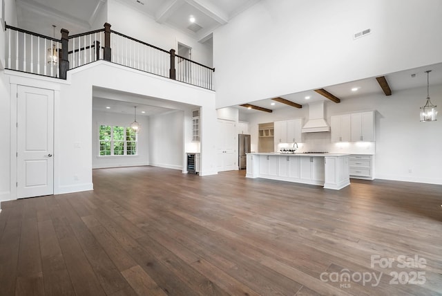 6712 Cove Ln, Sherrills Ford, NC 28673 - unfurnished living room with beam ceiling, dark wood-style floors, baseboards, a towering ceiling, and a chandelier