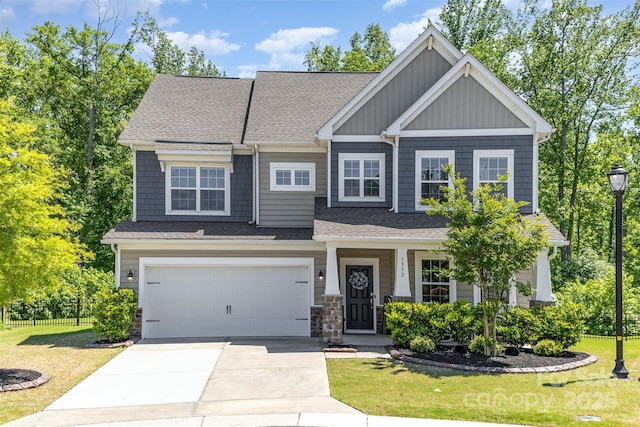 craftsman-style home featuring roof with shingles, fence, a front lawn, a garage, and driveway