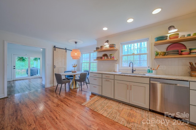 kitchen with open shelves, ornamental molding, a barn door, a sink, and dishwasher