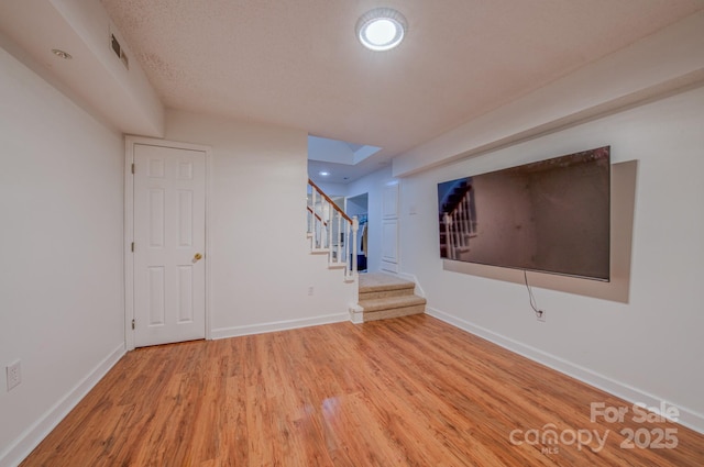 interior space featuring baseboards, light wood-style flooring, visible vents, and stairway
