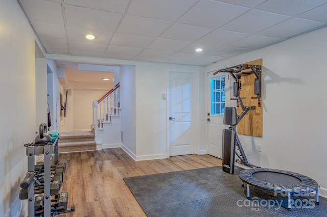 exercise area featuring recessed lighting, baseboards, a drop ceiling, and wood finished floors