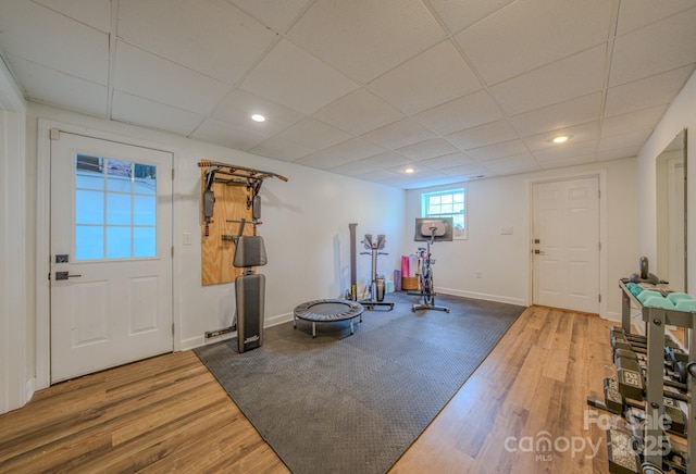 workout area featuring baseboards, recessed lighting, wood finished floors, and a paneled ceiling