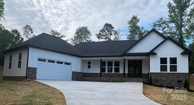 view of front facade featuring french doors, driveway, brick siding, a garage, and board and batten siding
