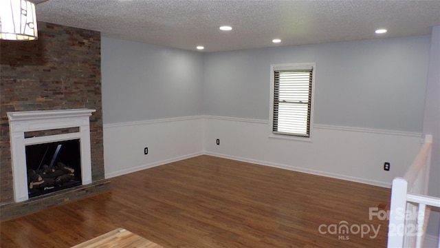 unfurnished living room featuring recessed lighting, wood finished floors, a textured ceiling, and a fireplace
