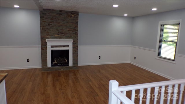 unfurnished living room with recessed lighting, wood finished floors, and a large fireplace