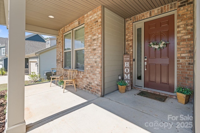 entrance to property featuring covered porch and brick siding