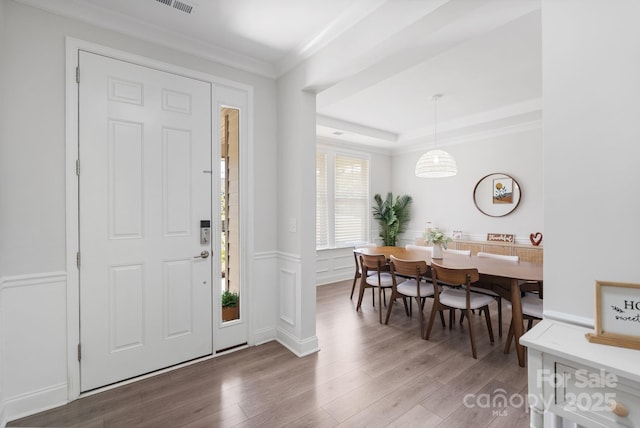 entryway featuring visible vents, wood finished floors, ornamental molding, and wainscoting