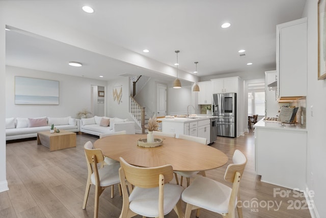 dining area with light wood finished floors, recessed lighting, and stairway